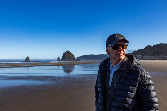 Portrait of senior man on beach with Haystack Rock in background