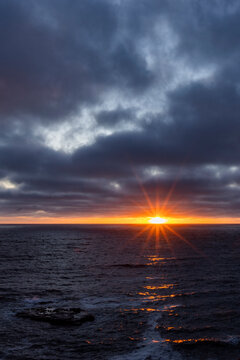 Dark clouds and sun stetting above ocean