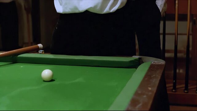 Close-up of a billiard ball on a green felt table with cues in the background