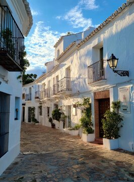 Whitewashed buildings line a cobblestone alleyway under a clear blue sky
