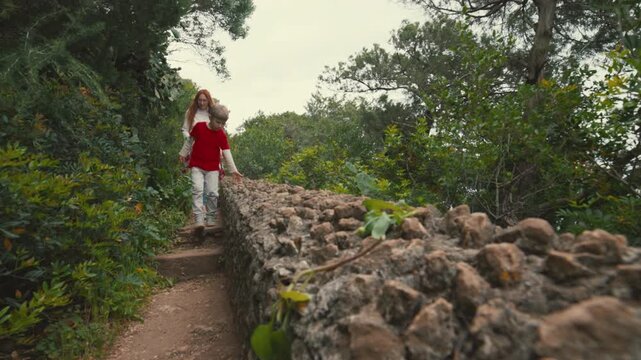 Mother and son walking on a stone path in a lush green park