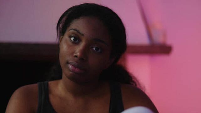 African American woman looking toward camera with calm thoughtful expression showing quiet confidence self awareness and gentle emotional presence in indoor home setting