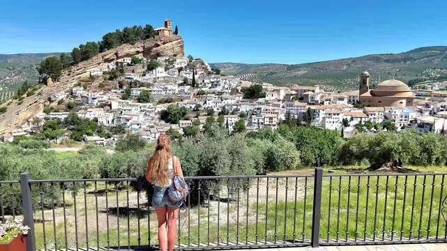 drone pull back shot revealing a woman tourist looking at the white village of Montefrio in Granada, Spain