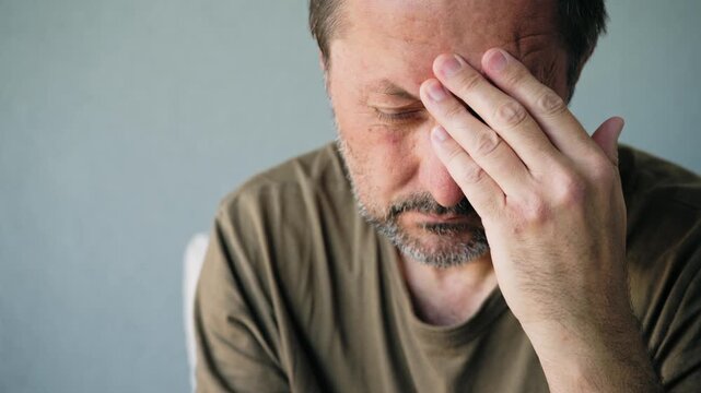 Middle-aged man suffering from headache and stress holding his temple in pain close-up portrait, 4K