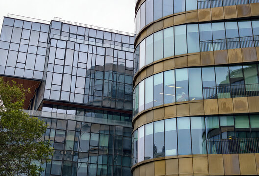 Modern buildings blend glass and metal in an urban setting on a cloudy day
