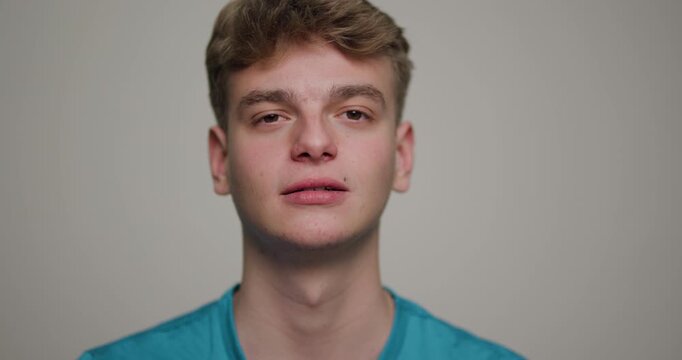 Confident young man with a relaxed demeanor against a plain background showcasing self-assured expressions during personal reflection moments