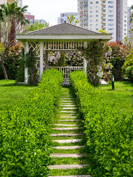 Garden path leads to a gazebo surrounded by greenery in a city park