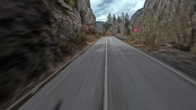 FPV drone flying fast along a winding mountain serpentine road, hugging sharp curves and steep slopes, dynamic aerial perspective with dramatic landscape, sense of speed, motion and scenic highland