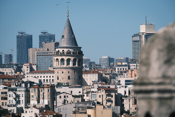 Fototapeta premium Galata Tower and Istanbul cityscape across the Golden Horn, framed by traditional stone domes and chimneys of Suleymaniye Mosque in the foreground, Turkey.
