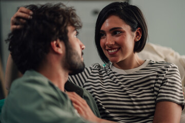 Obraz premium Young couple displaying love and affection while relaxing at home, enjoying an intimate and happy moment together
