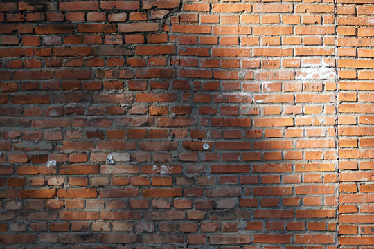Old red brick wall with sunlight casting shadows