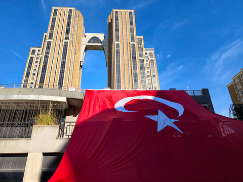 Large Turkish flag displayed in front of tall buildings under blue sky during daytime