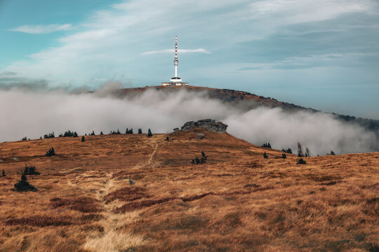 Distant view of Praded transmitter tower rising above low clouds