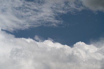 Fototapeta premium Soothing daytime sky with light clouds gently gliding across blue horizon. Quiet and peaceful sky during daytime featuring fluffy clouds smoothly drifting in clear blue sky