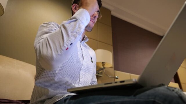 Young businessman working on laptop in modern hotel room and reacting to good news with excitement and happiness. Happy man celebrating success while using computer show achievement and motivation