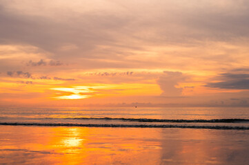 Obraz premium A stunning sunset over the ocean with golden light reflecting on the calm, wet shoreline at dusk.
