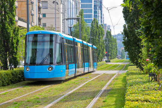MODERN BLUE TRAM ON GREEN TRACK IN URBAN CITYSCAPE - Eco friendly public transport with electric tram, sustainable mobility, commuting and urban travel concept - Europe, Norway, Oslo
