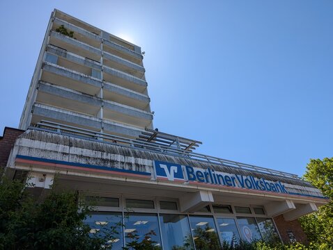 Eingang einer Berliner Volksbank Filiale an der Mehrower Allee mit einem Hochhaus im Hintergrund