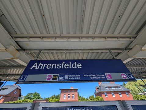 Bahnhofsschild Berlin-Ahrensfelde mit urbaner Verkehrsinfrastruktur im Berliner Umland