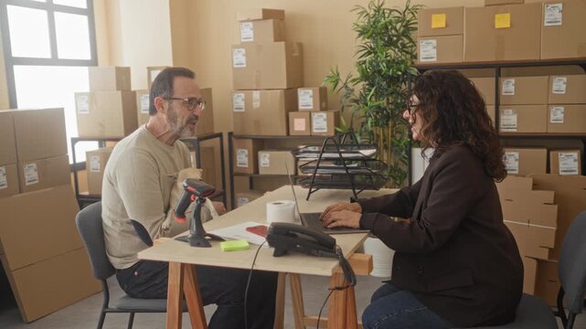 Man holding dog shakes hand with woman across small business desk with parcels, laptop and barcode scanner in building; trust partnership.