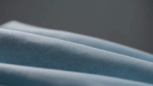 Water drops create a soft light pattern on a textured blue fabric material backdrop, forming an artistic design on the surface