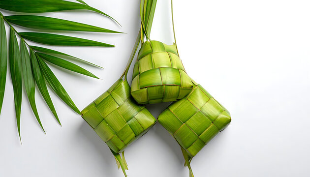 Traditional ketupat rice cakes made from woven palm leaves, served with fresh green palm fronds, eid al-fitr celebration food, culinary, malaysia