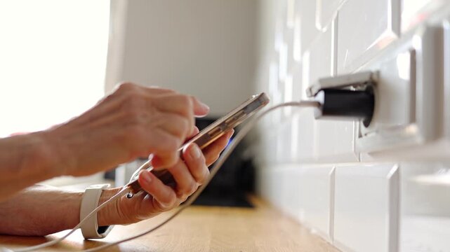 Senior Woman Charging Mobile Phone at Home
