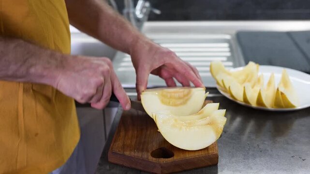 Man cutting ripe yellow melon into slices on wooden board in modern video kitchen Full HD