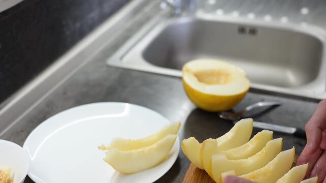 Fresh sliced yellow melon arranged on wooden cutting board in kitchen Full HD video