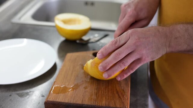 Man cutting ripe yellow melon into slices on wooden board in modern Full HD video kitchen