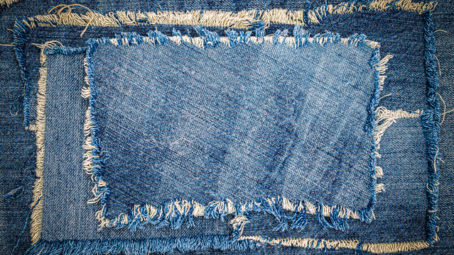 Denim patches layered on fabric showing various shades of blue and frayed edges in a textile workshop