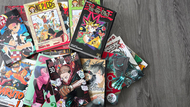 Overhead view of Viz and Dark Horse manga including Yu-gi-oh, Jujutsu Kaisen, and Berserk against a gray wood background, May 28, 2026, Schaumburg IL