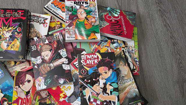 Pile of Shonen Jump manga books including Demon Slayer jumbled on wood floor, May 28, 2026, Schaumburg IL