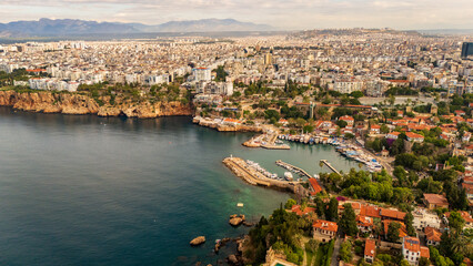 Naklejka premium drone aerial of Antalya marina harbor bay and the steep coastal cliffs. Beautiful marine landscape and Mediterranean resort town lifestyle scenery in Turkey