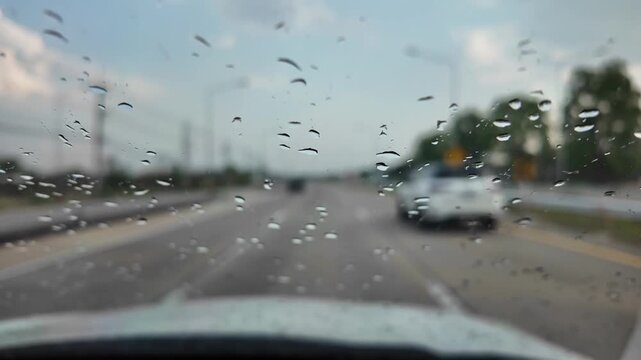Raindrops on Car Windshield: A close-up view of raindrops clinging to a car's windshield, blurring the view of a wet road and passing vehicles, evoking a sense of travel during inclement weather.