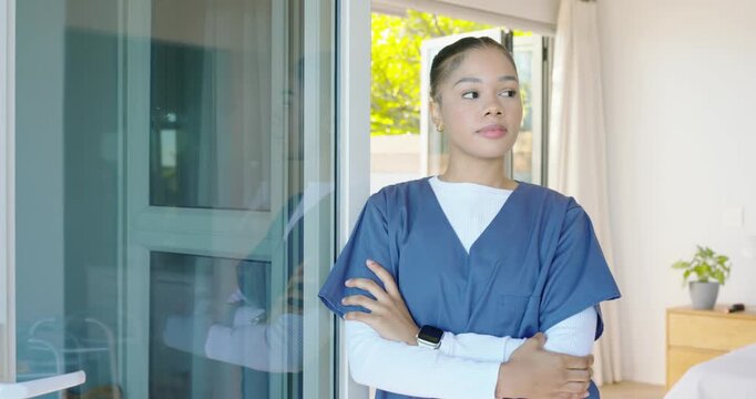 Camera tightening African American woman in scrubs standing at sliding door, looking up, reflecting