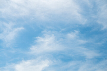 Fototapeta premium Clear blue sky filled with thin, spreading white clouds. Soft white clouds on a sunny summer day.