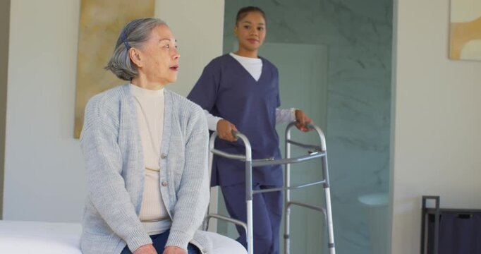 Senior woman sitting bed reaching walker as adult female caregiver entering door guiding standing