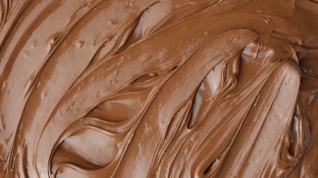 Macro texture of glossy chocolate nut cream swirling patterns