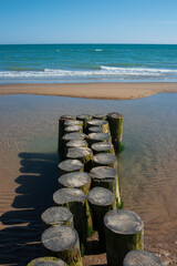 Obraz premium Wooden Groyne Breakwater On Sandy Beach – Symmetrical Coastline Horizon Landscape