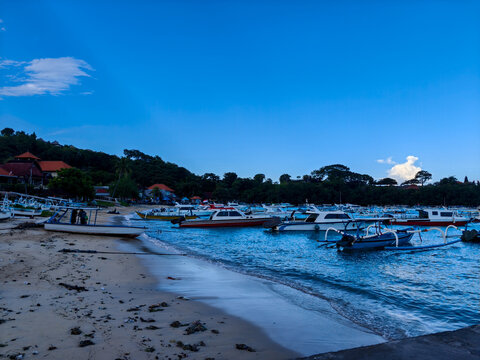Traditional jukung outriggers and fast boats anchored near the shore of Padangbai beach, Bali, Indonesia