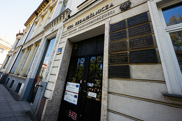 Naklejka premium Historic craft chamber entrance with ornate plaques and classical facade in Katowice, Poland showing signage, office names and urban architecture on a slanted street perspective