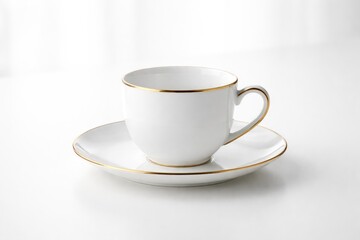 Fototapeta premium Sleek white ceramic cup and gold-edged saucer set on an immaculate white background for kitchenware and drink product display