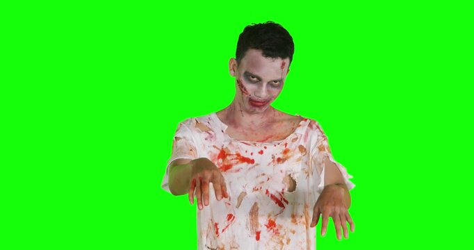 Scary zombie man with bloody makeup walking isolated on green screen background