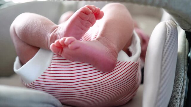 Close up view of cute newborn baby legs and feet crossed inside a comfortable stroller