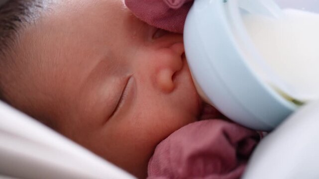 Extreme close up of a sweet newborn baby drinking milk from a feeding bottle