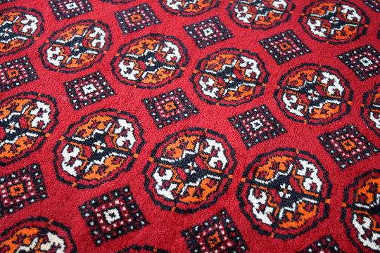 Traditional red Turkmen carpet with Tekke guls pattern close up, handmade wool rug texture detail macro of oriental tribal ornaments from Turkmenistan 