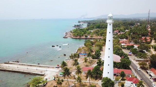 High Angle Aerial View of Historic White Lighthouse on Tropical Coastline with Turquoise Water