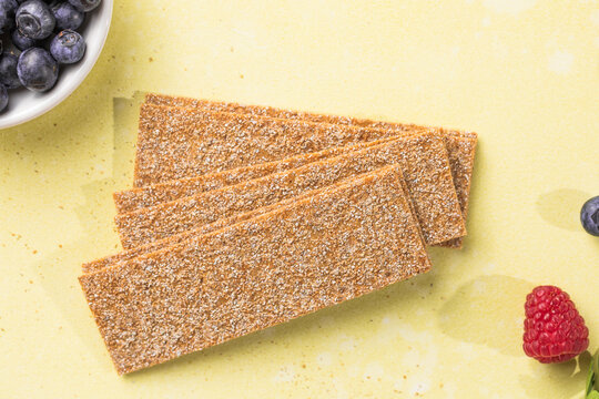 Fresh crunchy rye crispbreads with different toppings on green table, top view