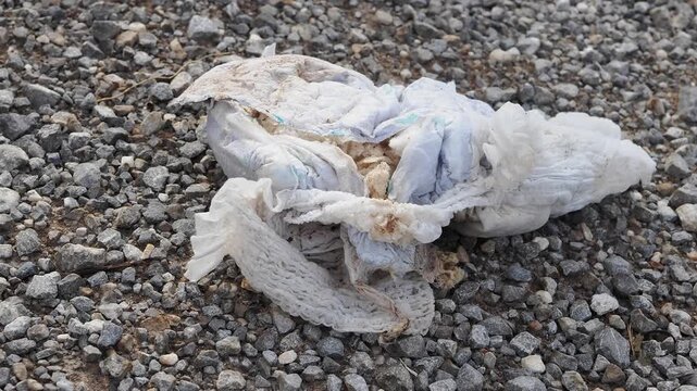 Used diapers discarded on the ground are dirty and constitute waste, posing a health hazard and attracting pests.